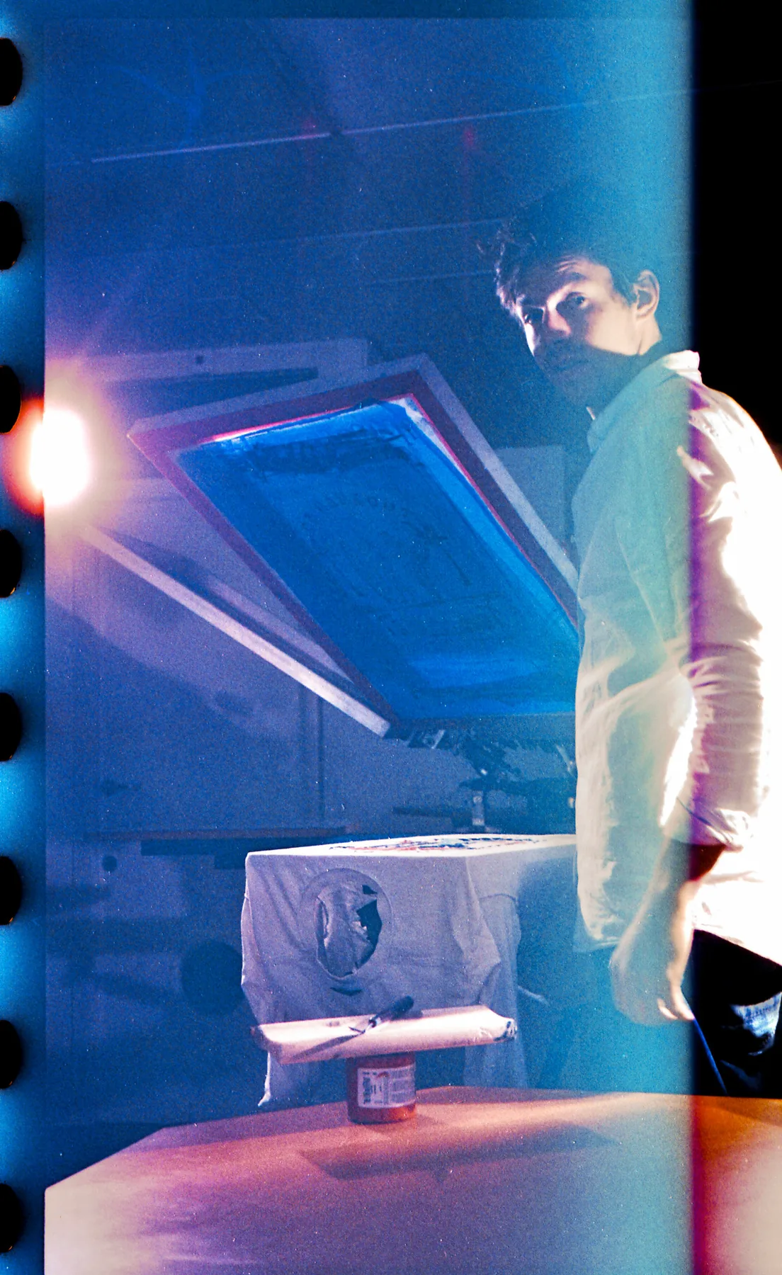 Screenprinter holding a frame in blue analogue light