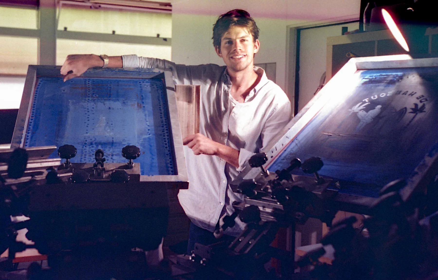 Bontjas screenprinter standing between two printing screens in the studio