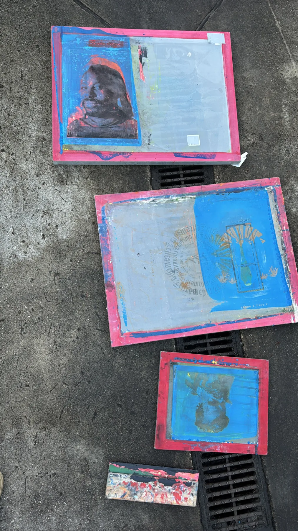 Three used screenprinting frames drying outside on wet pavement